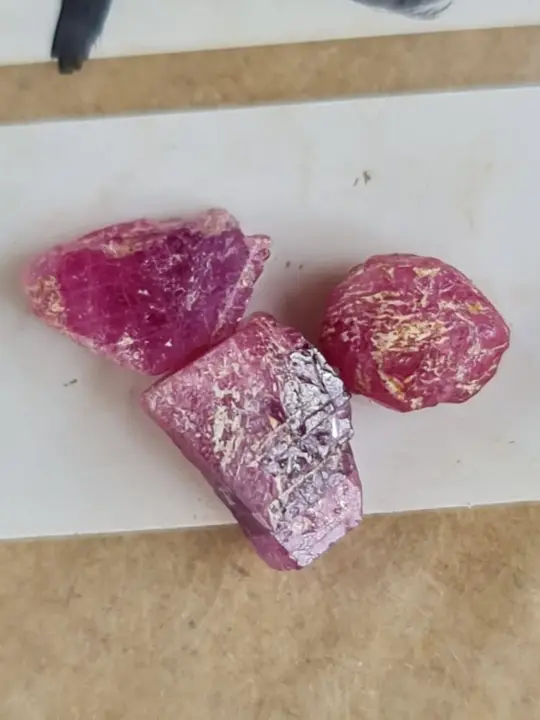 Três rubis em bruto sobre papel